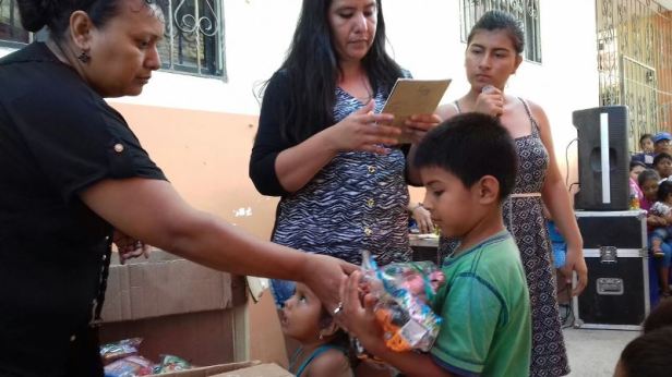 Un niño recibe juguetes de manos de una vocal del comité de su barrio en San Mateo de Manta. Manabí, Ecuador.