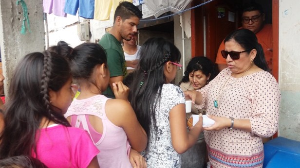 La presidenta del Patronato municipal de Montecristi, Mercy Santos de Quijije, reparte un desayuno escolar a niños de su cantón. Manabí, Ecuador.