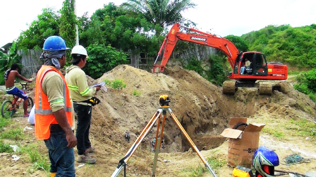 Con una máquina retroexcavadora se hace la zanja para enterrar el nuevo colector de aguas servidas en la Ciudadela Urbirríos de Manta. Manabí, Ecuador.