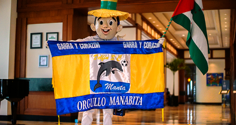 Bandera oficial del Delfín S. C. de Manta, sostenida por un maniquí que representa al ciudadano popular de la provincia de Manabí, cuya bandera también enarbola. Manabí, Ecuador.