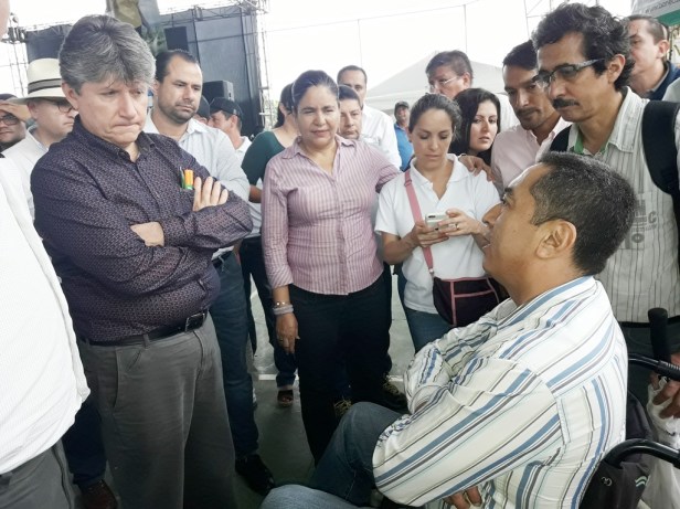 El ministro de Agricultura y Ganadería, Rubén Flores Agreda, conversa con un productor agropecuario postrado en una silla rodante. Manabí, Ecuador.
