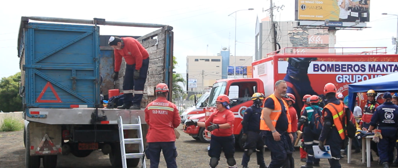 Bomberos de Manta y delegados de Bomberos Unidos Sin Fronteras, de España, en un momento previo a un simulacro de salvamento en una estructura colapsada. Manabí, Ecuador.