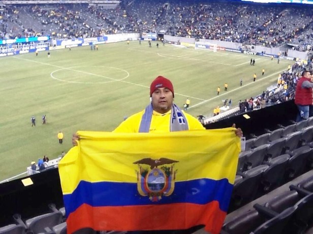 Joselías Sánchez junior muestra la bandera del Ecuador dentro de un estadio de fútbol.